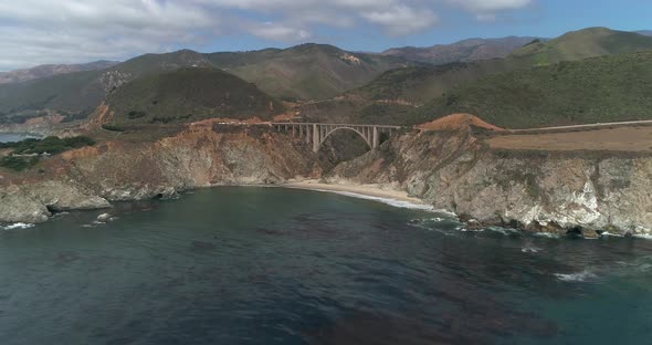 Aerial Drone Stock Video of Bixby Bridge Highway with water and shore below in Big Sur Monterrey Cal