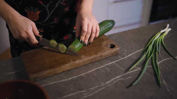 Female Hands Cuting Cucumber on Wooden Board in Kitchen