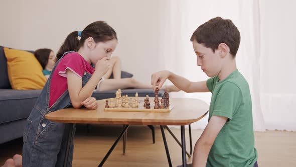 Young kids playing Chess on the living room table