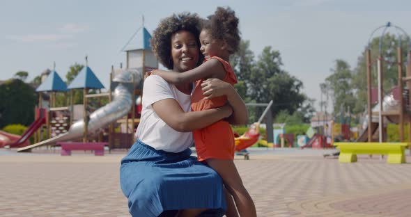 Side View of African Little Girl Run Into Her Mother Arms Outdoors