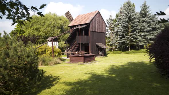 Wooden mill and waterpump in a garden with evergreens,Czechia,zooming.