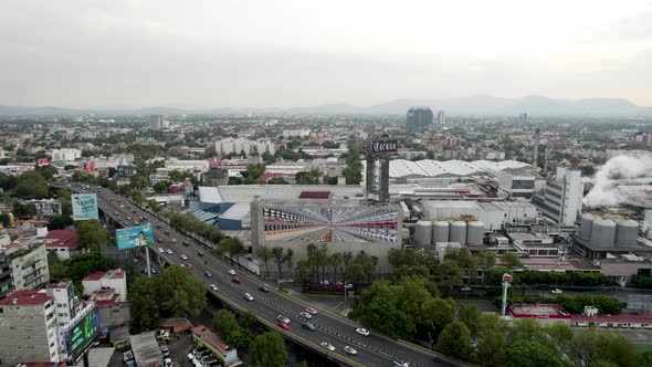 backwards drone shot of beer factory and morning commute and car traffic mexico city
