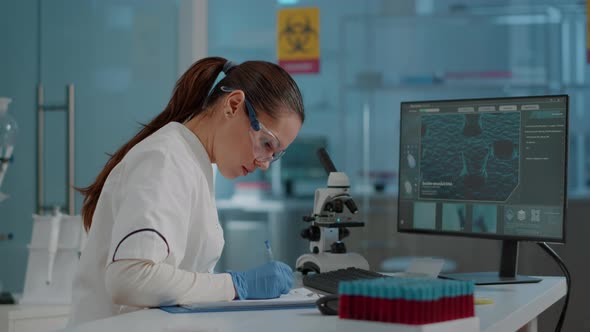 Biology Researcher Using Computer and Taking Notes