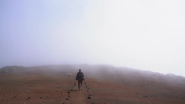 Man Walking Along Stony Ground Under Misty Sky