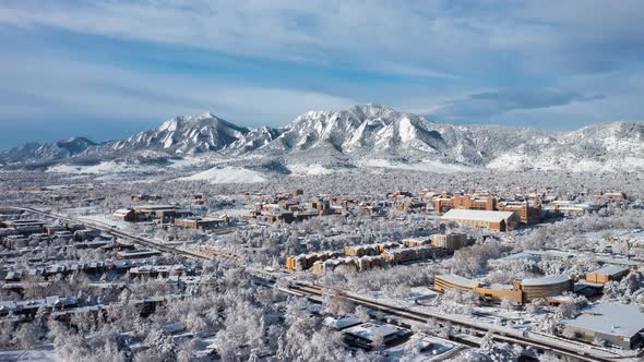 Aerial time lapse of downtown Boulder Colorado and CU Boulder with snow and ice covered mountains af