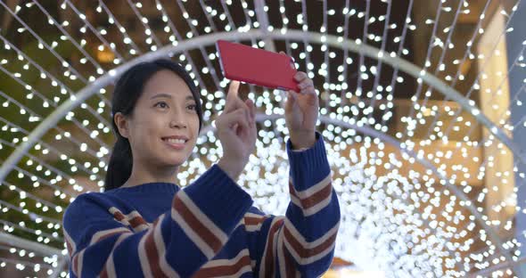 Woman use of the phone for take photo with the christmas decoration at night