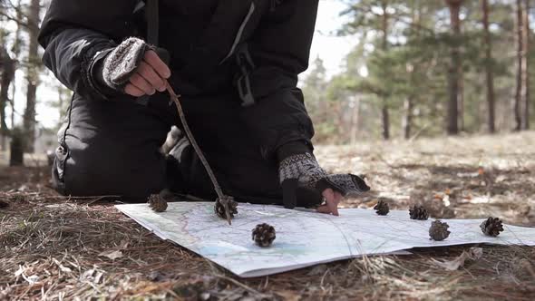 Orienteering in the forest. Tourist on a hike in a forest park with a map.