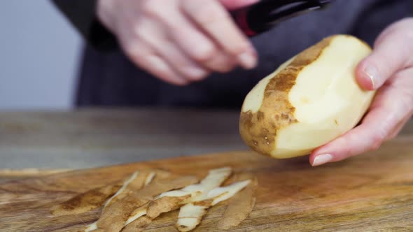 Peeling organic yellow potatoes with potato peeler