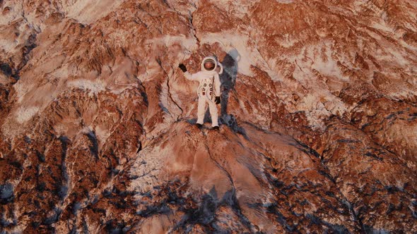 Astronaut Standing on a Rock Waving Hand