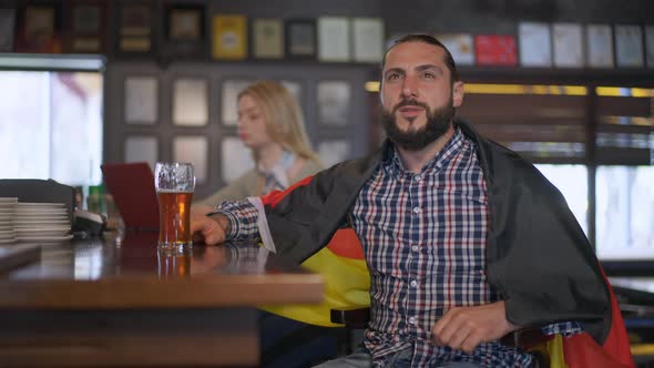 Thrilled Excited Caucasian Brutal Bearded Man Rejoicing Sport Team Victory Sitting with German Flag