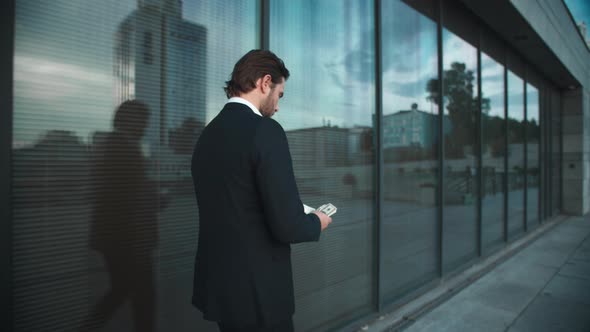 Businessman with Money Walking on Street. Male Professional Counting Money