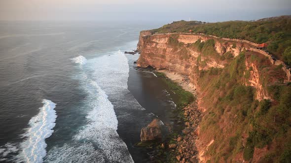 Sunset in Uluwatu Coastline in Bali Indonesia with Beautiful Rocky Cliffs and Wavy Sea