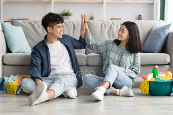 Tired asian couple sitting on floor, giving high five / Photodune, Misc