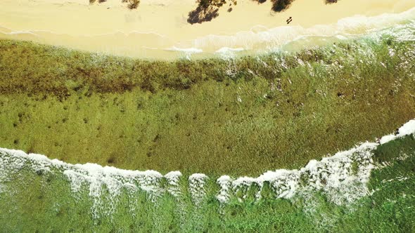 A couple walking along the tropical beach in Thailand. Waves rolling on the sandy shore