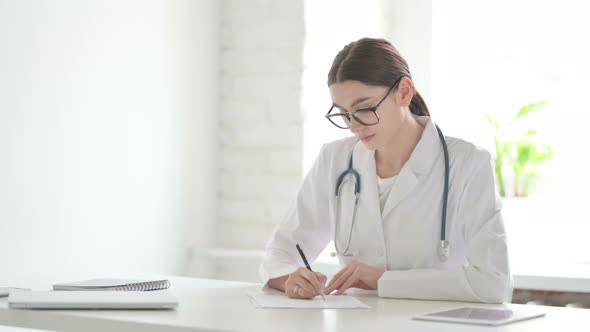 Female Doctor Writing on Paper in Office