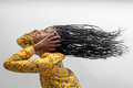 Side view of carefree African American female with long flying braided hair on gray background - PhotoDune Item for Sale