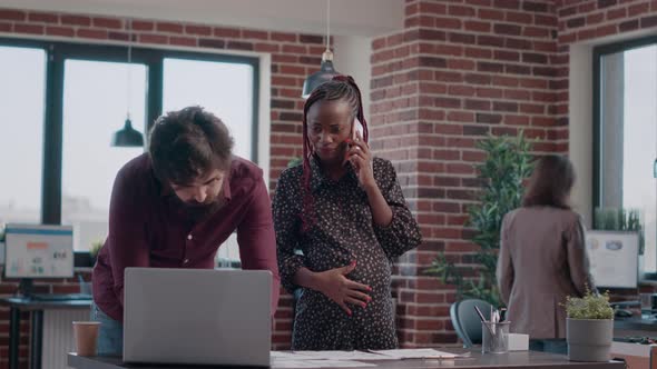 Pregnant Woman Talking on Phone Call While Man Using Laptop