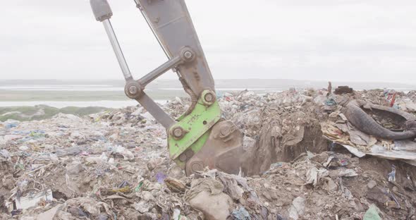 Digger clearing rubbish piled on a landfill full of trash