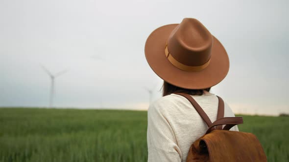 Young tourist in a hat looking at wind turbines