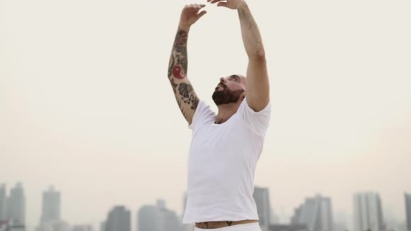 Male Yogini Extending His Arms High As He Stretches In An Up And Down Motion