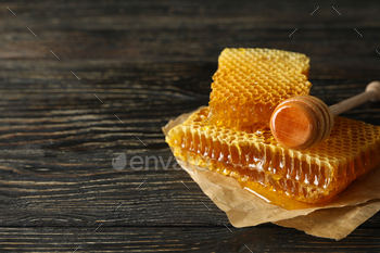 Baking paper with honeycomb pieces and dipper on wooden background / Photodune, Misc