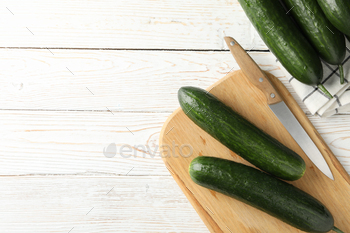 Board and towel with cucumbers and knife on wooden background, space for text / Photodune, Misc