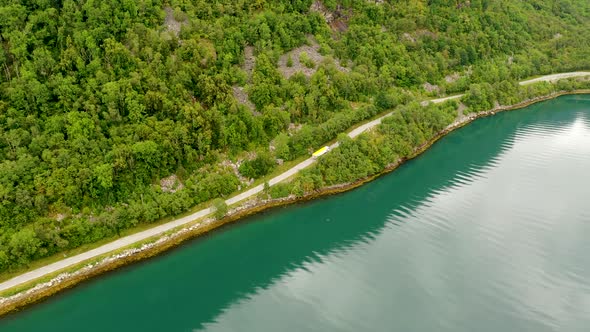 Aerial view of Logistics Truck transporting Cargo on a Scenic Route by a lake