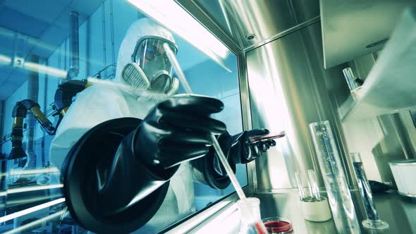 Scientist in a Hazmat Suit is Using a Vacuum Cabinet for Analysis