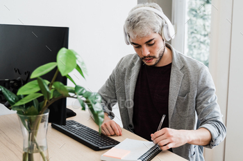 ホーム オフィスで働きながらコンピューターとヘッドフォンを使用して流行に敏感な若い男 / Photodune, Misc