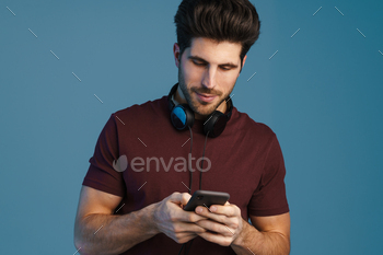 Pleased handsome man with headphones using mobile phone / Photodune, Misc