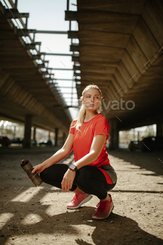 Athletic woman relaxing after workout holding a water bottle. / Photodune, Misc