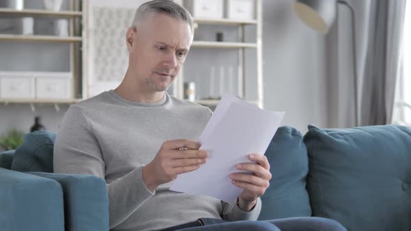 Gray Hair Man Reading Documents While Sitting on Sofa Paperwork
