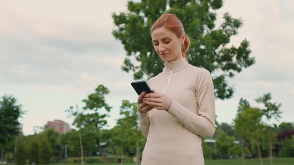 Woman holding mobile phone while morning workout, gym exercises.