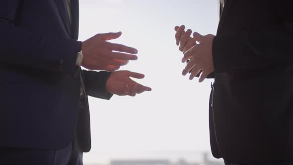 Unrecognizable Businessmen Talking and Shaking Hands on Sunny Day