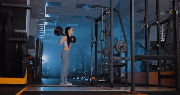 Girl in the Gym Doing Squats with a Barbell. Smoke, Darkness, Sports Hall