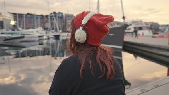 Unrecognizable Young Woman in Headphones Enjoying Beautiful Sunset Over the Sea Rear View