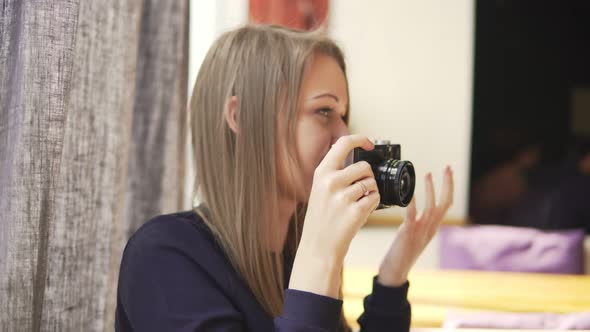 Young Girl Taking Photos with Vintage Camera in Cafe Having Fun