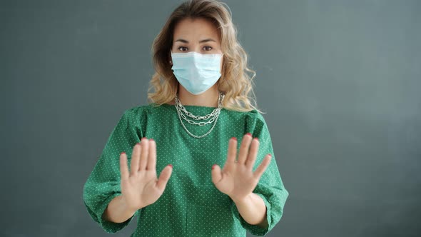 Slow Motion of Young Woman Wearing Medical Face Mask Gesturing with Disapproval and Rejection