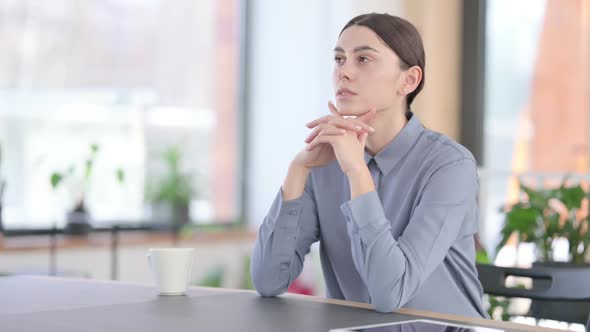 Young Latin Woman Sitting in Office and Thinking