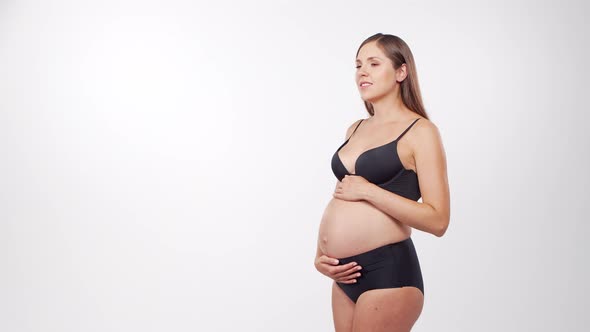 Young, happy and healthy pregnant woman in front of white background.