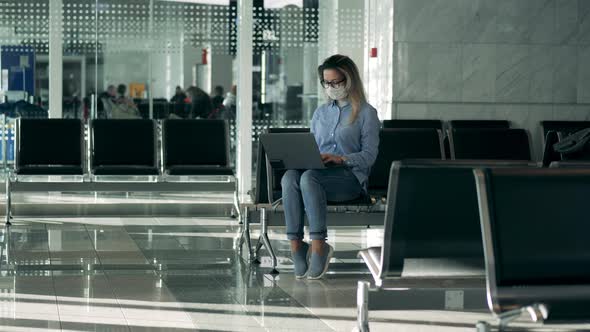 Airport Lounge with a Lady Wearing a Medical Mask and Using a Laptop