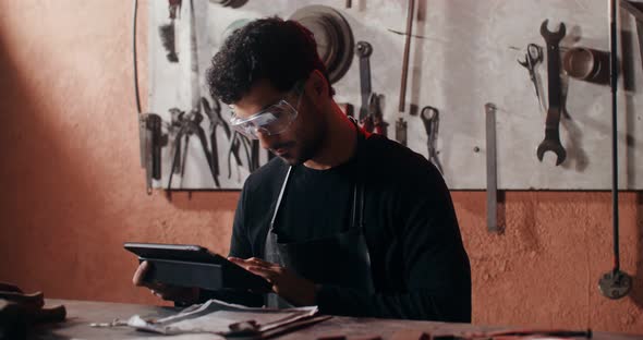 A Blacksmith Uses a Tablet to Create a Sketch of a Future Product