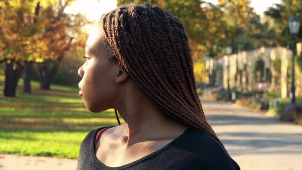 Young Beautiful Black Woman Looks Around in the Park in Autumn Day - Closeup