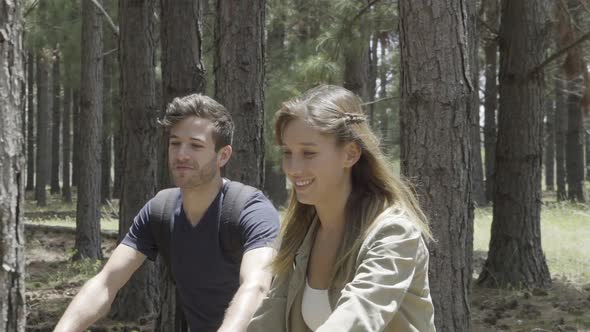 Young couple riding bicycles through forest