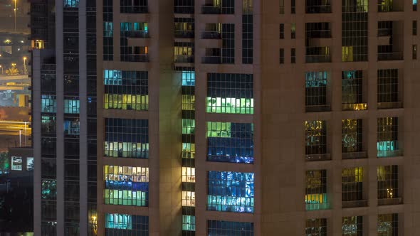 Windows of the Multistorey Building of Glass and Steel Lighting Inside and Moving People Within