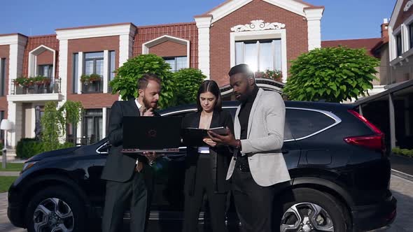 Business People in Formal Attire Discuss Business Processes while Standing Near Black Car