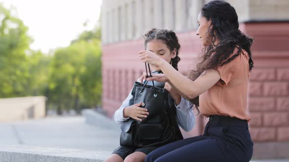 Mother Hispanic Woman with Daughter Baby Sits Outdoors Preparing for School Class