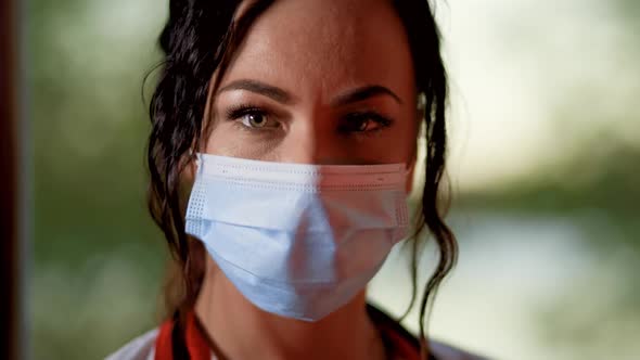 Close Face View of Young Female Doctor or Nurse Wearing Surgical Mask and Looking at Camera