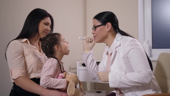 Smiling Doctor Examining Throat of Small Patient