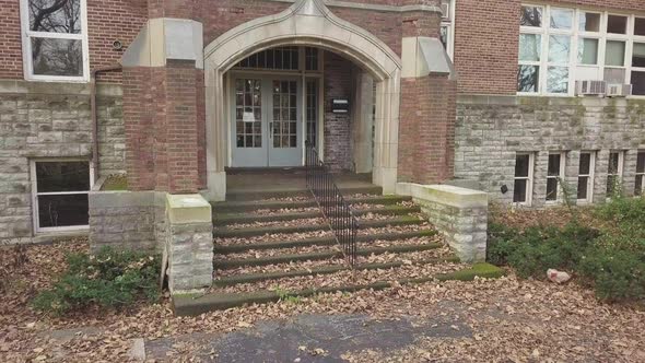 Smooth pan of outdoor historic brick building and entryway on autumn day.